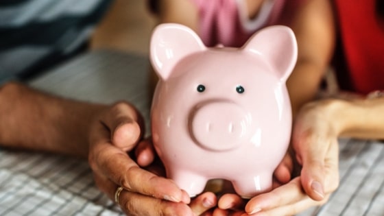 two people hold pink piggy bank