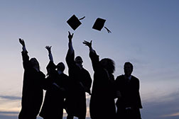 Students throwing their graduation caps upwards in celebration.