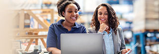 Warehouse worker and her supervisor smiling while using a laptop.