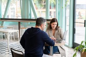 Woman and man sitting at table looking at a laptop.