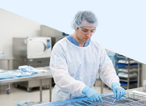 Man in scrubs and PPE arranging tools for surgery.