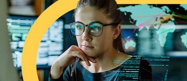 Woman in glasses coding on computer in office.