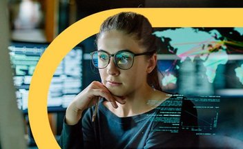 Woman in glasses coding on computer in office.