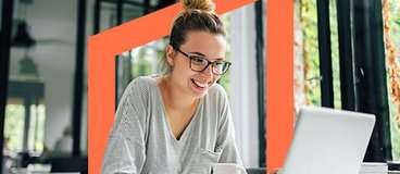 Girl with glasses smiling at white laptop.