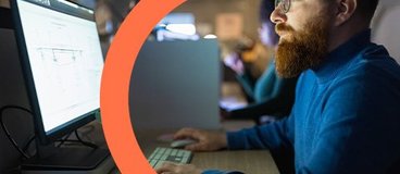 Man with beard and glasses working on computer.