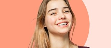 high school aged girl smiling on orange background.