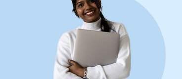 girl in white sweater holding silver laptop.