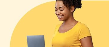 woman in a yellow t-shirt working on a laptop.