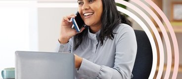 Woman on phone call in front of small laptop.