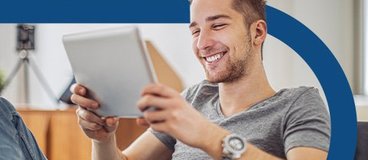 Man in grey t-shirt holding tablet.