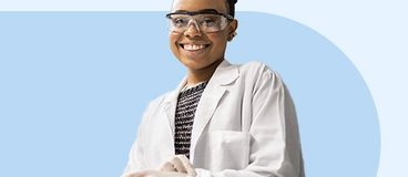 Smiling woman in white lab coat and safety goggles.