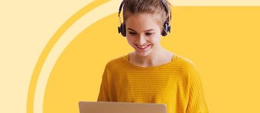 girl in yellow sweater with headphones using a laptop on yellow background.
