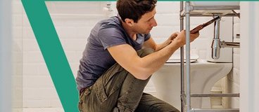 Man working on pipes on bathroom sink.