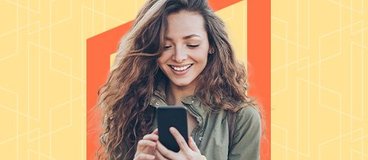 A woman holds a phone and looks at it, smiling