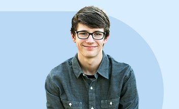 Boy in button up shirt and glasses smiling.