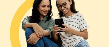 mom and daughter smiling looking at cell phone.