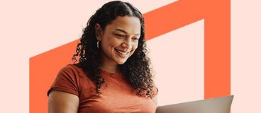 woman in an orange shirt working on a laptop.