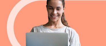 student with silver laptop smiling.