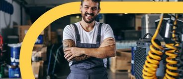 Auto mechanic posing for photo behind vehicle.