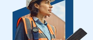 Woman in orange safety vest and white hard hat using tablet.