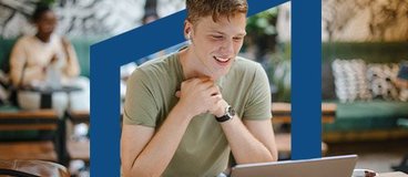Man in tshirt studying with laptop at a cafe.