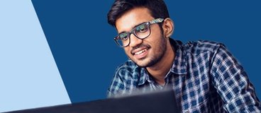 Man in blue shirt with glasses using laptop.