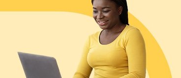 Girl in yellow long sleeve shirt and jeans using laptop.