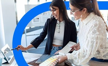 Two women reviewing designs on tablet.
