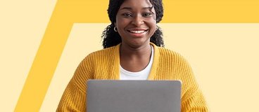 Girl in yellow sweater using silver laptop.
