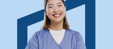Woman in blue scrubs smiling on blue background.