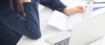 woman sitting at a desk looking at papers.