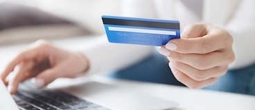 woman holding a credit card while on the computer