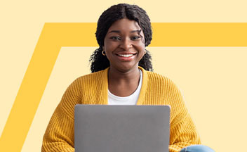 Girl in yellow sweater using silver laptop.
