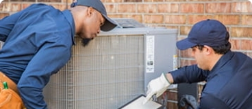 HVAC technicians inspecting an outdoor unit.