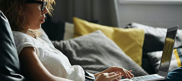 Teen sitting on couch using laptop.