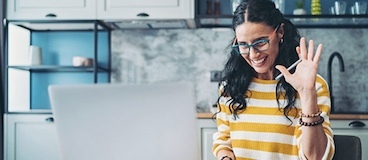 woman on a computer smiling and waving.