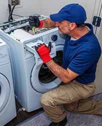 appliance repair technician fixes laundry machine.