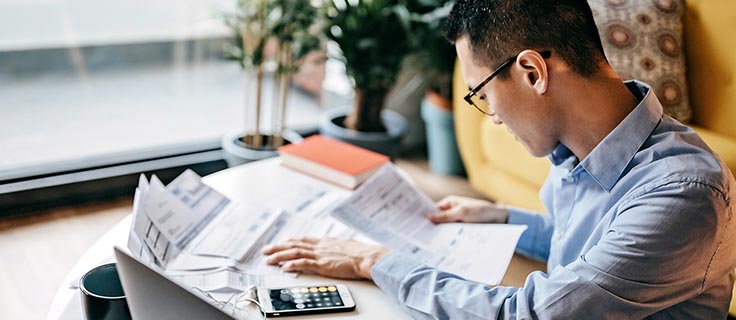man sitting at a desk with papers and a calculator.