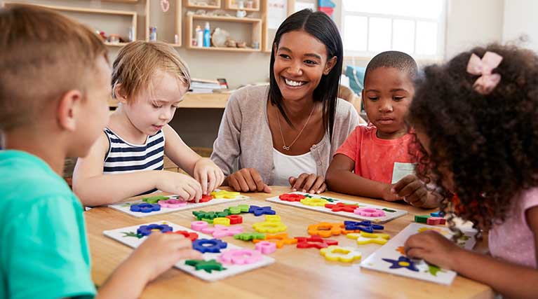 early childhood educator sitting with students.