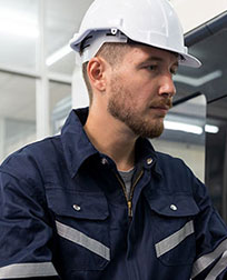 man in white hardhat operating CNC machine.