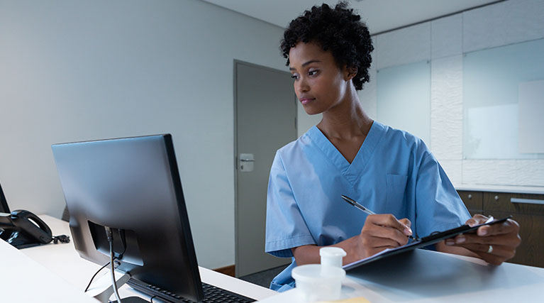 medical records technician reading computer screen and taking notes.