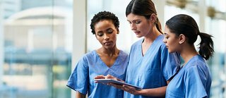three healthcare students look at computer tablet.