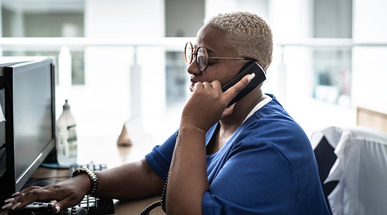 medical administrative assistant on phone at desk.