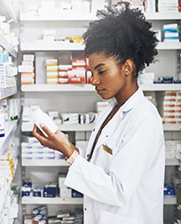 pharmacist reading prescription bottle in pharmacy.