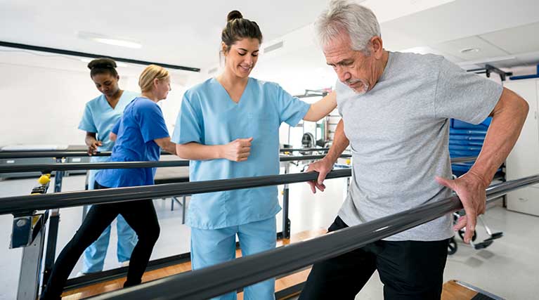 physical therapist helping patient use walking bars.