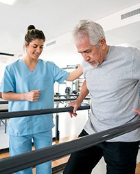 physical therapist helping patient use walking bars.
