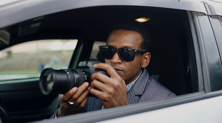private investigator in a car with a camera.