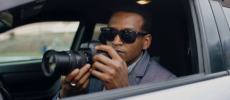 private investigator in a car with a camera.