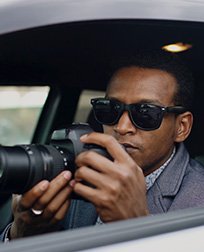 private investigator in a car with a camera.
