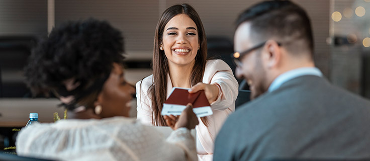 travel agent handing passports and tickets to couple.